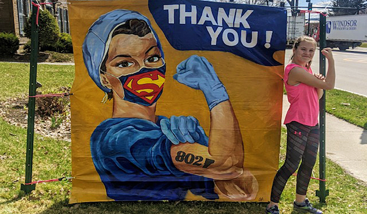 Thank you mural with picture of nurse, symbolic of Rosie the Riveter, with and 802/VT state tattoo and superman emblem on her face mask.
